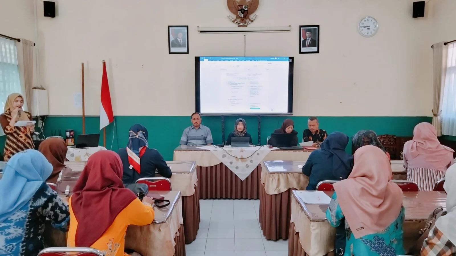 Ruangan seminar sekolah dengan penceramah dan peserta guru yang menyimak presentasi